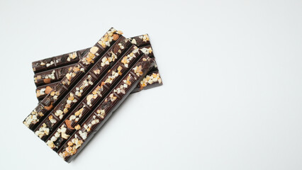 Chocolate bar pieces with nuts on white background. Selective focus.