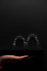 Two orthodontic aligners held by a doctor's hand in the dental office. Dental props. Modern methods of dental treatment