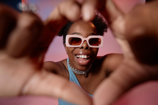 Happy woman gesturing heart shape with fingers