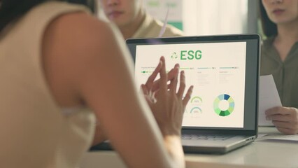 A business team in a meeting discussing ESG (Environmental, Social, and Governance) initiatives displayed on a laptop.