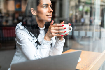 Young business woman drinking coffee in a cafe in the city