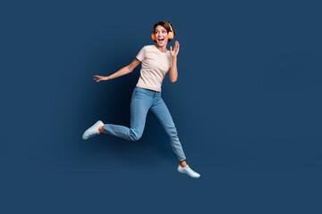 Full size photo of attractive young woman run jump dance earphones dressed stylish white clothes isolated on dark blue color background