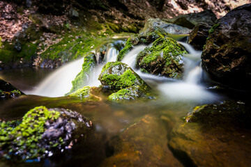 Fototapeta na wymiar Waterfall between rocky stream in the mountains