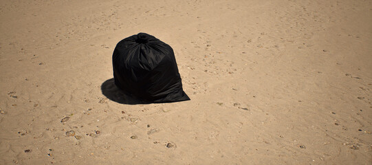 Black garbage bag left on tropical beach with rippled sand. - 746436991