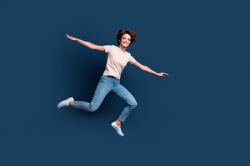 Fototapeta na wymiar Full size photo of attractive young woman jump run spread hands wear trendy white clothes isolated on dark blue color background