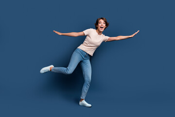 Fototapeta na wymiar Full size photo of attractive young woman flying have fun spread hands dressed stylish white clothes isolated on dark blue color background