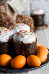 Closeup of glaze decorated Easter cakes and yellow colored eggs on a plate.