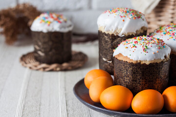 Glaze decorated Easter cakes and orange colored eggs on a plate closeup.