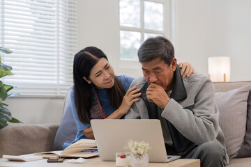 A retired Asian couple sits stress as they calculate their monthly expenses on the living room sofa.