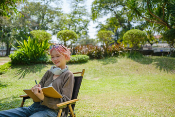 Woman among nature wearing glasses and head phone reading a book.