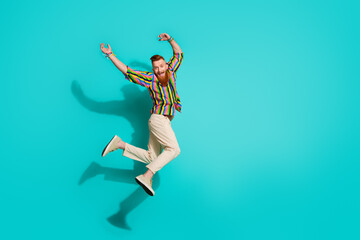 Full length size photo of energetic guy celebrating holidays raised arms up jumping red hair hipster isolated on blue color background