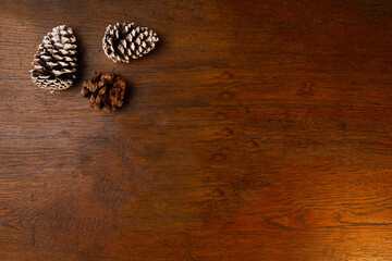 Old wooden background with dark texture and Christmas pine cones.