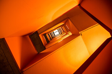 Orange rectangular spiral staircase with vanishing point