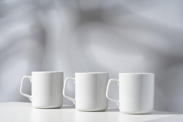 Fototapeta na wymiar White ceramic mugs on gray background with shadows