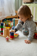 Toddler playing with toys on floor at home. Children learning in game. Domestic room, everyday life