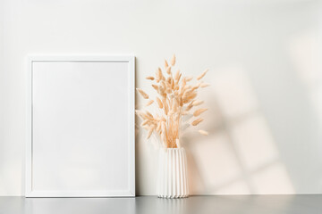 Blank picture frame and dried flower in a vase on white background