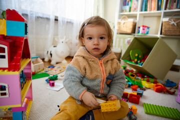 Toddler playing with toys on floor at home. Children learning in game. Domestic room, everyday life