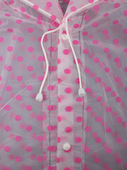 Close-up fragment of a pink polka dot raincoat with laces and buttons.  Comfortable clothes concept.