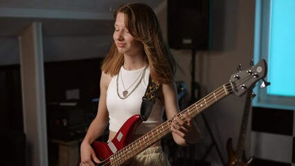 Slow motion. Portrait of a young girl playing her favorite rock song on the bass guitar and smiling