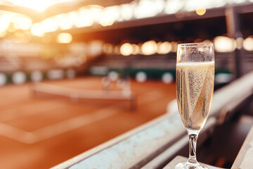 Wineglass with sparkling beverage stands on armrest offering perfect point to savor view of tennis...