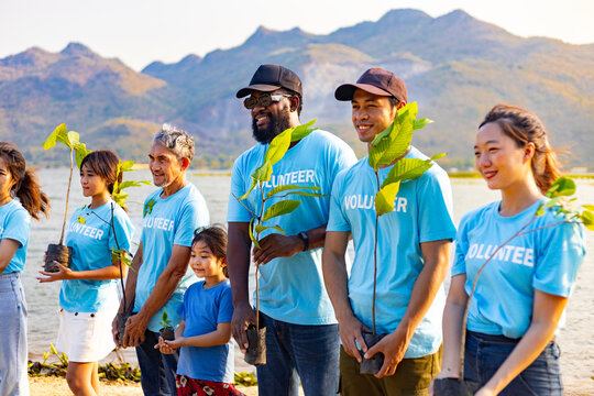 Team of young and diversity volunteer worker group enjoy charitable social work outdoor in tree forest planting NGO work for fighting climate change and global warming coastline habitat project