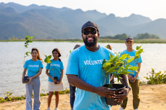 Team of young and diversity volunteer workers group enjoy charitable social work outdoor in tree forest planting NGO work for fighting climate change and global warming coastline habitat project