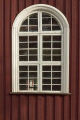 Old weathered window with arch on a old wood building.