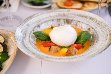 Mozzarella di buffalo on a plate with cherry tomatoes, tomato sauce, basil leaves 