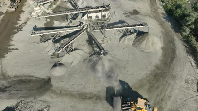 Aerial drone video of Gravel separator machine separates stone material into various fractions. Stone crusher plant machine. Conveyor belt in work process. Extraction of aggregates or gold from river