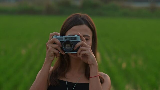 Portrait of a young woman with a retro camera in the rice field
