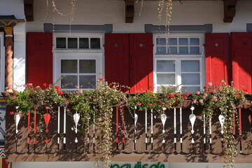 Balkon mit Blumenkästen, Fenstern und roten Fensterläden, Garmisch-Partenkirchen, Oberbayern, Bayern, Deutschland