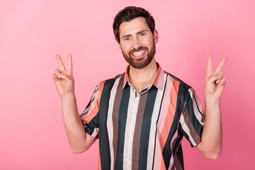 Portrait of satisfied glad young person toothy smile arms fingers demonstrate v-sign isolated on pink color background