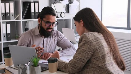 Focused office workers, businessman and business woman, engaged in teamwork brainstorming during work meeting in the office. Analyzing information and developing strategy.