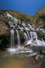 Fototapeta na wymiar Mae Ya Waterfall in Chiang Mai Province is a beautiful waterfall with water all year round and very high. Waterfall in a beautiful forest park in Thailand In February 2024