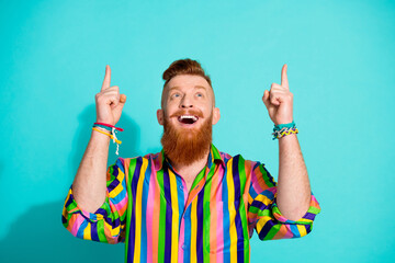 Photo of crazy red hair bearded guy in striped shirt pointing finger above head surprised ecommerce promo isolated on cyan color background