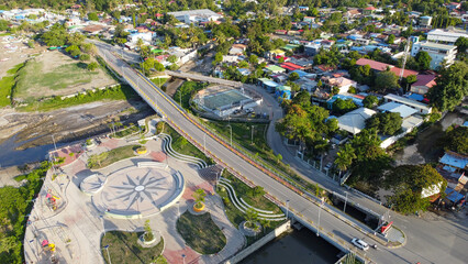 Aerial landscape view of the capital city of Dili, Timor-Leste in Southeast Asia with children's playground, bridge and houses amongst green trees
