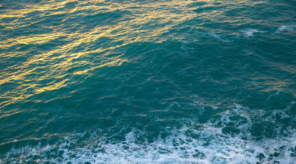 Overlooking the turquoise sea with wave and foam and golden color pouring on the sea, Cinque Terre, Italy