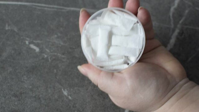 A woman opens a box of nicotine snus. 
