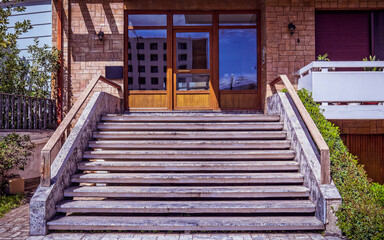 Stairs to a wood and glass entrance door of a contemporary luxury apartment building. Visit Athens posh downtown, Greece.