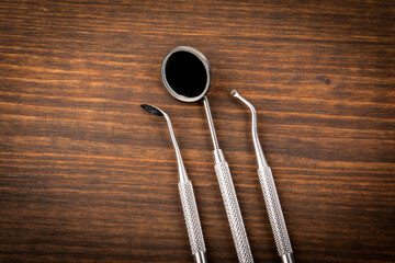 A set of dentist and dental hygienist tools on a dark wooden background