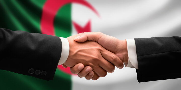 Businessman, diplomat in suits clasp hands for handshake over Algeria flag, agree on united success in trade, diplomacy, cooperation, negotiation, support, teamwork in commerce, gesture of greeting