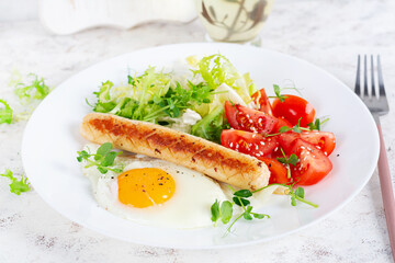 Fototapeta na wymiar Keto breakfast. Fried egg and chicken sausage and fresh salad.