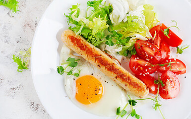 Keto breakfast. Fried egg and chicken sausage and fresh salad. Top view, flat lay