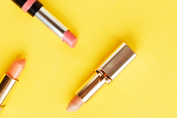 Set of pink lipsticks on bright yellow background flat lay top view minimal. Beauty and cosmetics...