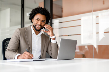 An African-American businessman exudes comfort and control as he engages in a phone conversation,...