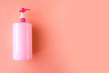 Bottle with pink dishwashing liquid on pink background. Minimal concept. Copy space for the text