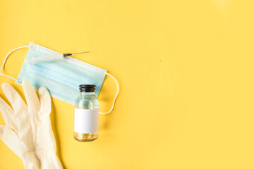 Face medical mask, hand sanitizer bottle and gloves on bright yellow background. Summer holidays...