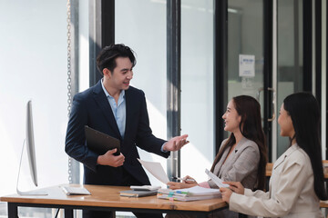 Young and smart CEO discussing the project with his team in the office room.