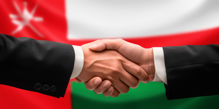 Businessman and diplomat in suits clasp hands for handshake over Oman flag, agree on united success in trade, diplomacy, cooperation, negotiation, support, teamwork in commerce, gesture of greeting
