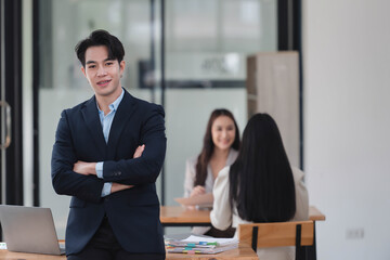 Young smart manager standing in the office room with arm crossing.